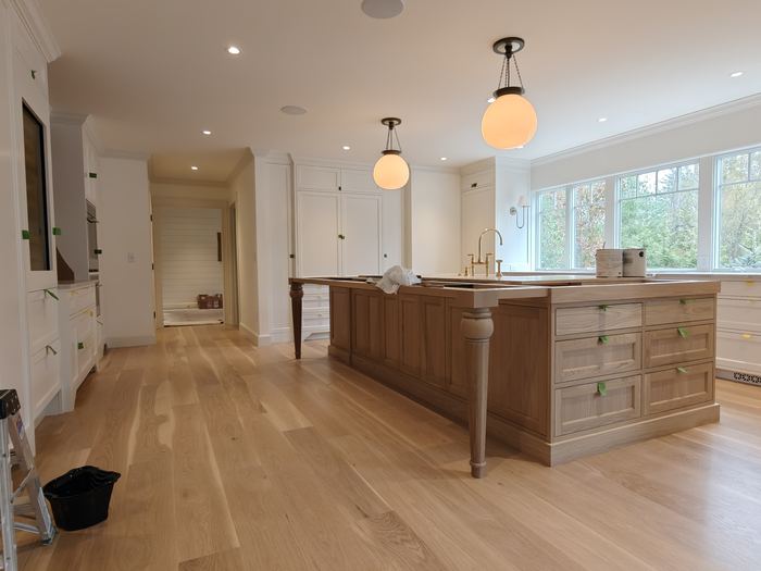 Bright kitchen with white cabinetry, wood island, pendant lights, and wide plank flooring.