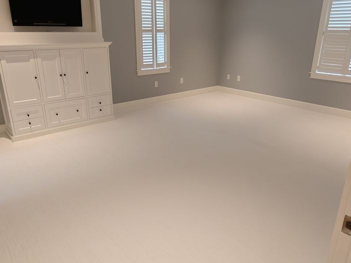 Finished room with gray walls, white built-ins, shuttered windows, and mounted TV.