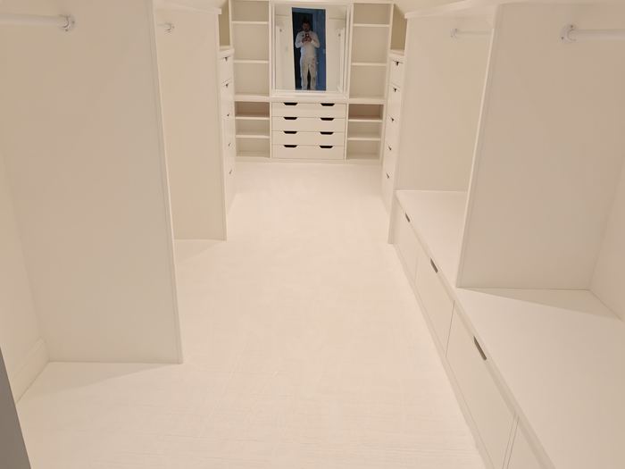 White walk-in closet with built-in drawers, shelves, hanging rods, and recessed lighting.